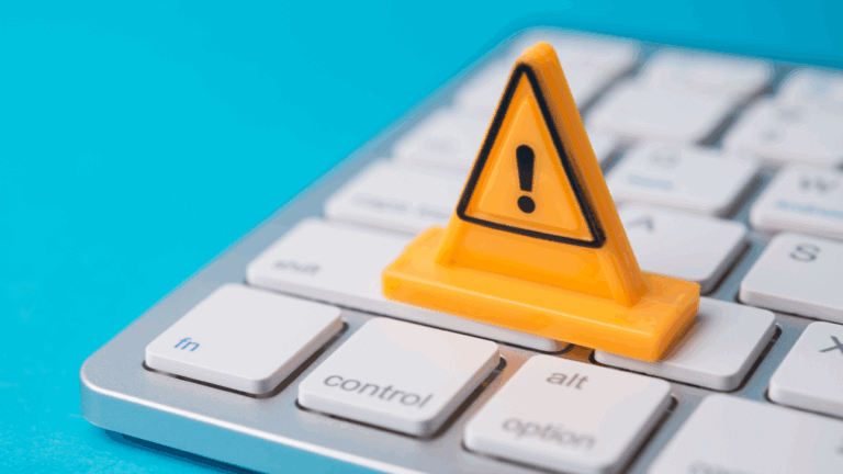 Closeup photo of a computer keyboard with a small alert sign on it.