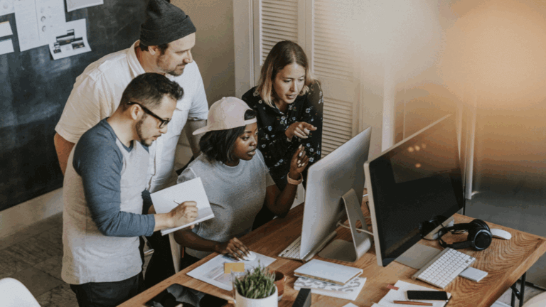 A team of web developers and designers working together around a computer.