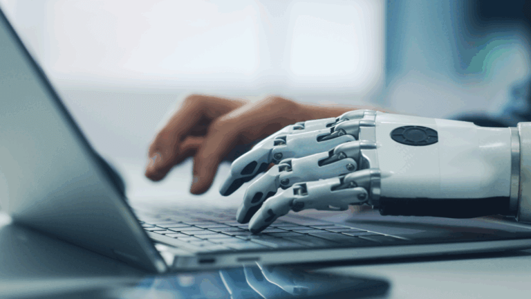 A closeup of human and robotic hands working on a laptop.