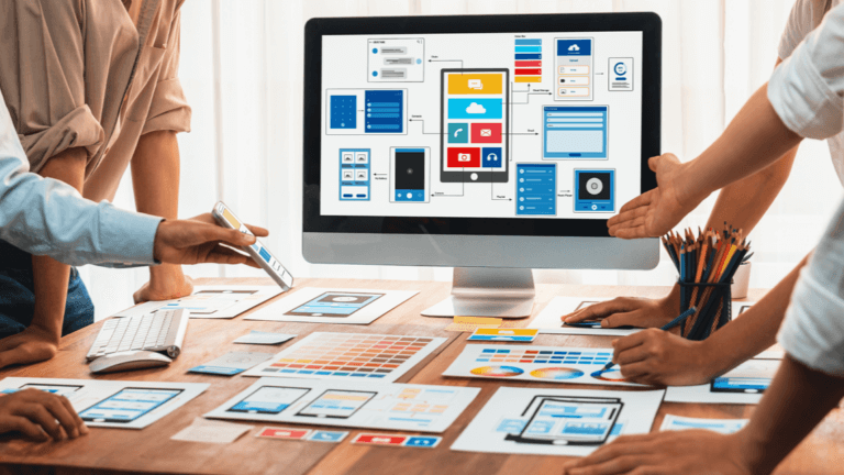 Design team collaborating on website interface layouts with wireframes and color palettes spread across workspace.