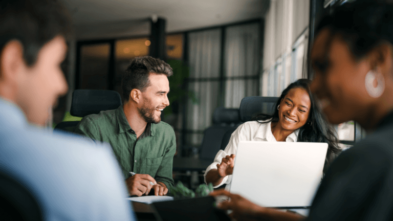 Client meeting in office with team collaborating around laptop.