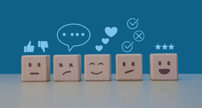 Row of wooden blocks showing different facial expressions with feedback icons above them.